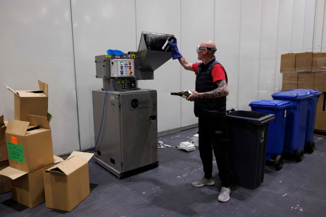 Behind the scenes at the judging of Decanter Awards in Excel today. Pictured: Gary inserts empty wine bottles into a machine that breaks them down into pieces to be discarded. (C) Belinda Jiao 07598931257 www.belindajiao.com jiao.bilin@gmail.com